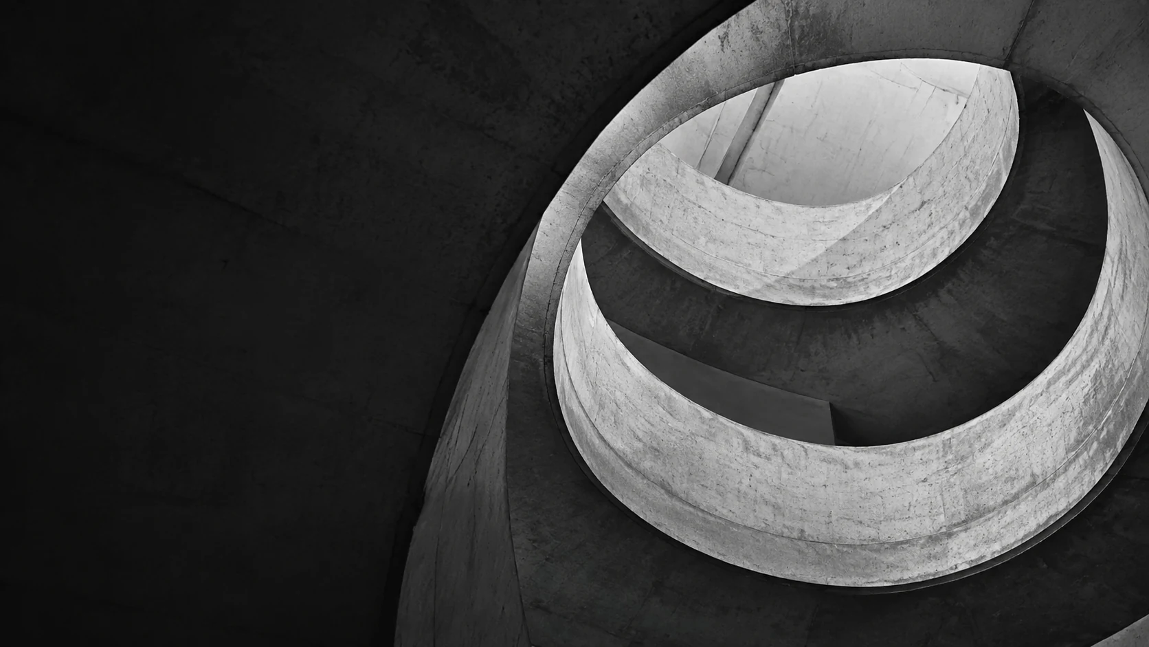 Sweeping concrete architecture in black and white, with deep shadows and sculptural curves.